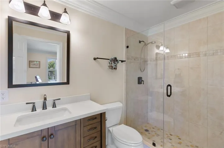 Bathroom with ornamental molding, vanity, and a shower stall