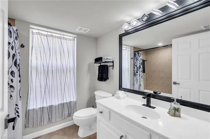 Bathroom with toilet, vanity, and tile patterned flooring