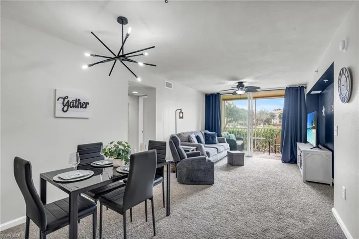 Living room featuring carpet flooring and ceiling fan with notable chandelier