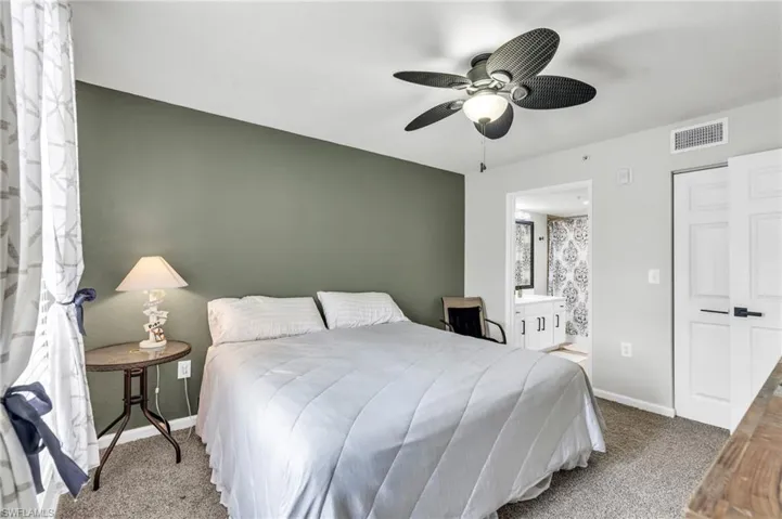 Carpeted bedroom with ceiling fan and connected bathroom