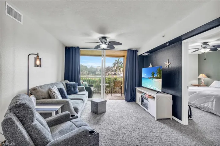 Carpeted living room with ceiling fan and a textured ceiling