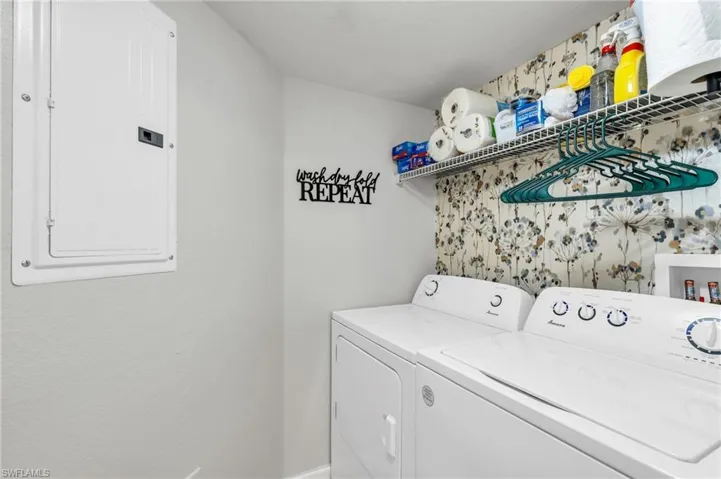 Laundry room with electric panel and washer and clothes dryer