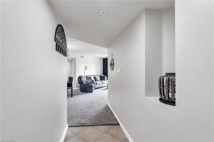 Hallway featuring light colored carpet