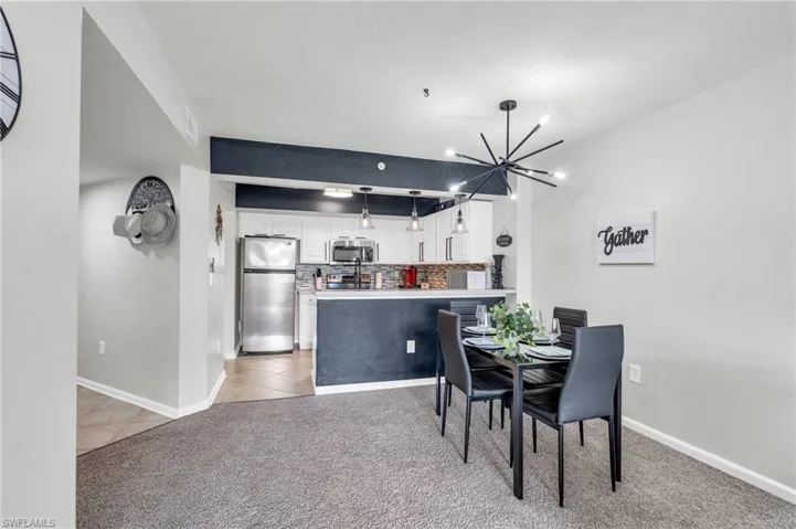Dining space with light carpet and a chandelier