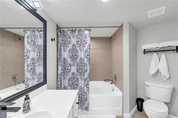 Full bathroom featuring toilet, vanity, tile patterned flooring, and shower / bath combo with shower curtain