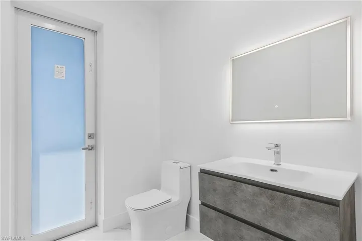 Half bathroom with toilet, marble finish floor, and vanity