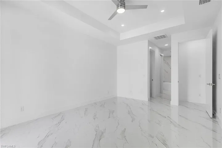 Empty room featuring visible vents, baseboards, a raised ceiling, and ceiling fan