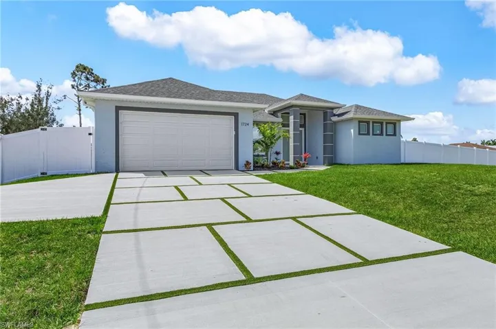 View of front of property featuring driveway, fence, stucco siding, and a front lawn