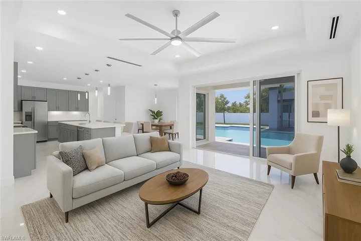 Living area featuring recessed lighting, a tray ceiling, marble finish floor, and ceiling fan
