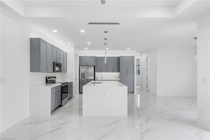 Kitchen with a sink, appliances with stainless steel finishes, marble finish floor, and gray cabinetry