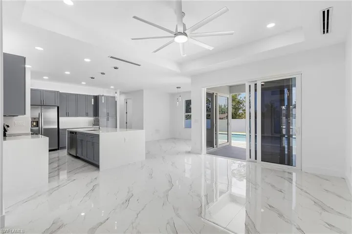 Kitchen with gray cabinets, a ceiling fan, visible vents, a tray ceiling, and appliances with stainless steel finishes