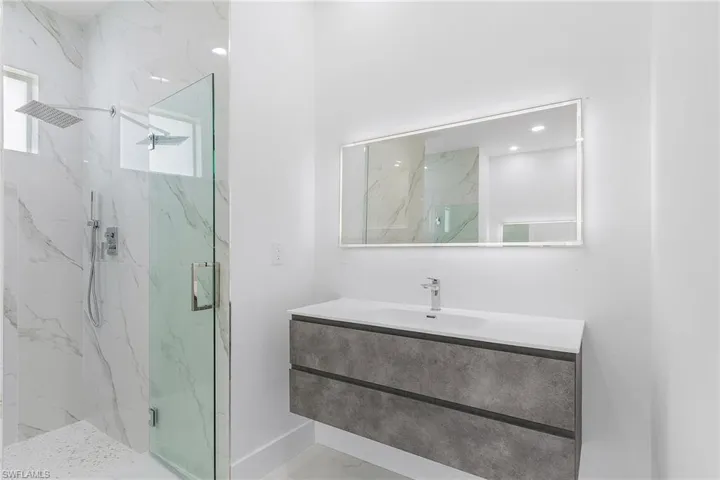 Bathroom with a marble finish shower, baseboards, and vanity