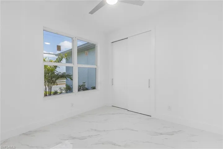 Spare room with a healthy amount of sunlight, marble finish floor, and a ceiling fan