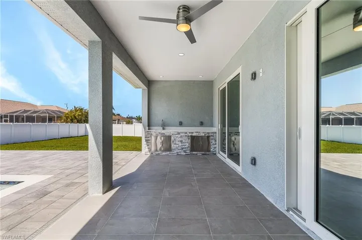 View of patio with an outdoor kitchen, ceiling fan, and fence