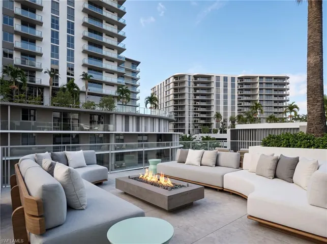 Rooftop terrace featuring a rectangular concrete fire pit, glass panel railing, and stone-finish flooring. Developer Rendering
