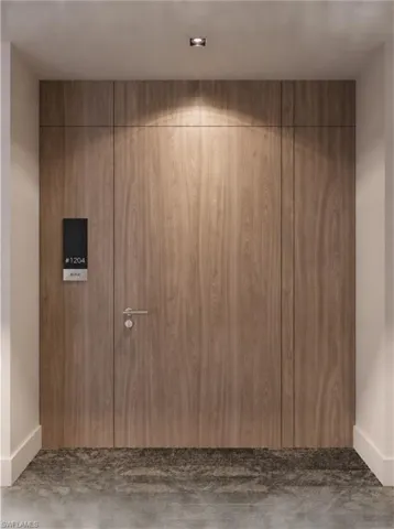 Full-height wood-finish paneling featuring a flush-mount door, satin-finish metal lever hardware, and recessed ceiling lighting. Developer Rendering