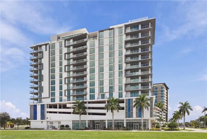 High-rise residential building featuring a concrete facade, floor-to-ceiling glass windows, private recessed balconies, and an integrated multi-level parking garage