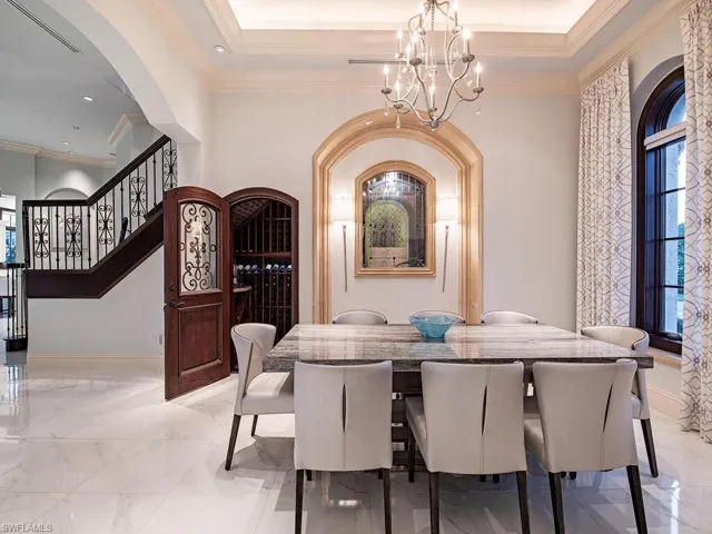 Tiled dining room featuring a tray ceiling, a chandelier, and crown molding