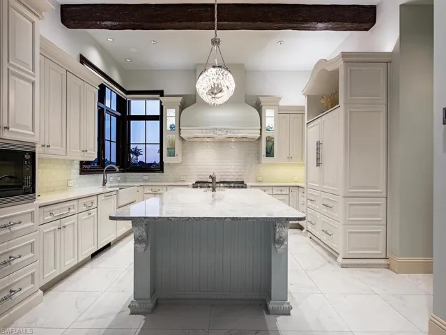 Kitchen with black microwave, backsplash, and light tile floors