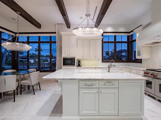 Kitchen with black microwave, backsplash, pendant lighting, double oven range, and sink