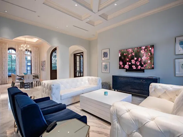 Living room featuring a chandelier, beam ceiling, crown molding, and coffered ceiling