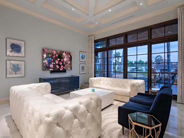 Living room featuring crown molding, beam ceiling, light tile flooring, a high ceiling, and coffered ceiling