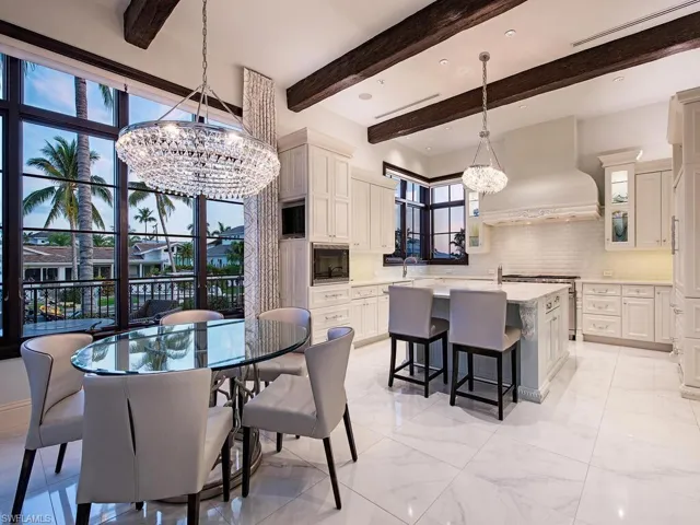 Tiled dining space featuring a notable chandelier, sink, and beam ceiling