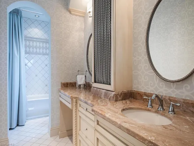 Bathroom featuring tile flooring, tiled shower / bath combo, and vanity with extensive cabinet space
