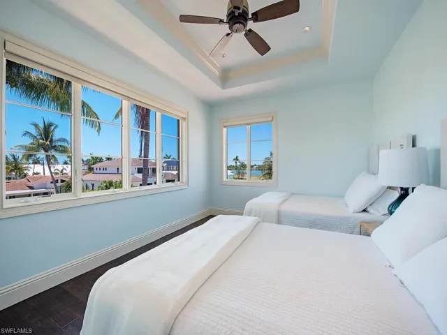 Bedroom featuring dark hardwood / wood-style flooring, ceiling fan, and a raised ceiling