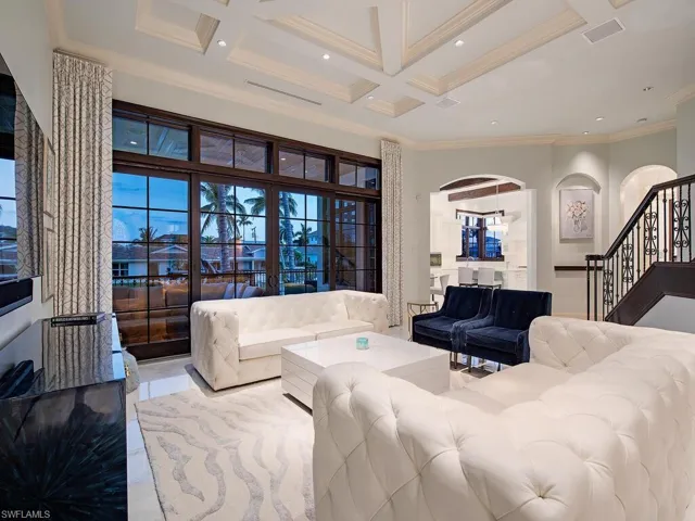 Tiled living room with a high ceiling, coffered ceiling, crown molding, and beamed ceiling