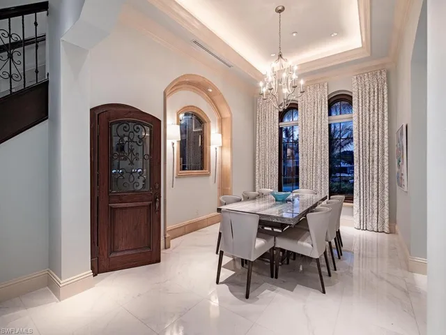 Dining area with an inviting chandelier, light tile floors, and a raised ceiling