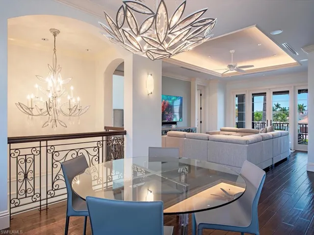 Dining area featuring dark hardwood / wood-style flooring, ceiling fan with notable chandelier, and a raised ceiling