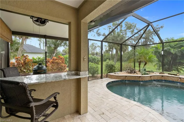 View of pool with grilling area with an outdoor bar and a patio area