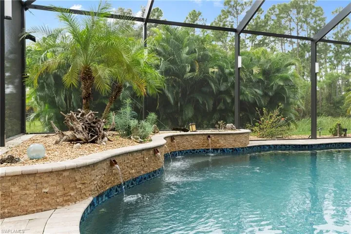 View of swimming pool with pool cage and pool water feature