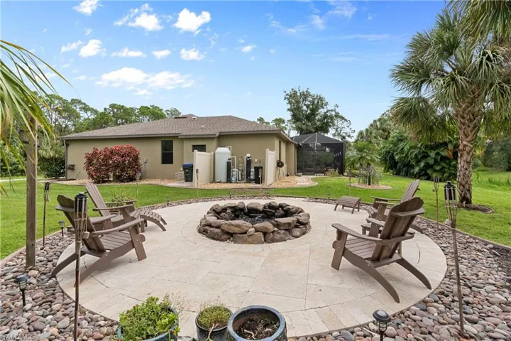 Rear view of property featuring a yard, a fire pit, and patio area