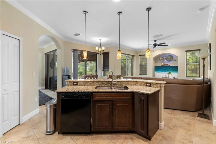 Kitchen featuring dark brown cabinetry, sink, pendant lighting, crown molding, and dishwasher