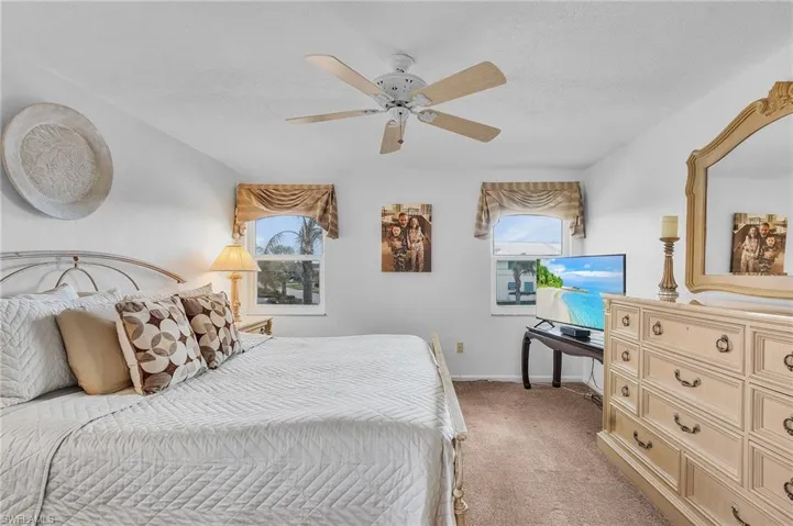 Bedroom featuring multiple windows, ceiling fan, carpet floors, and a textured ceiling