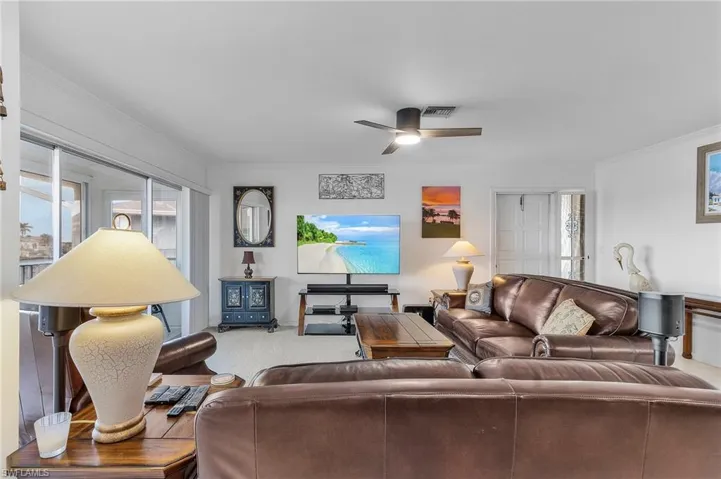 Living room featuring carpet flooring, crown molding, and ceiling fan