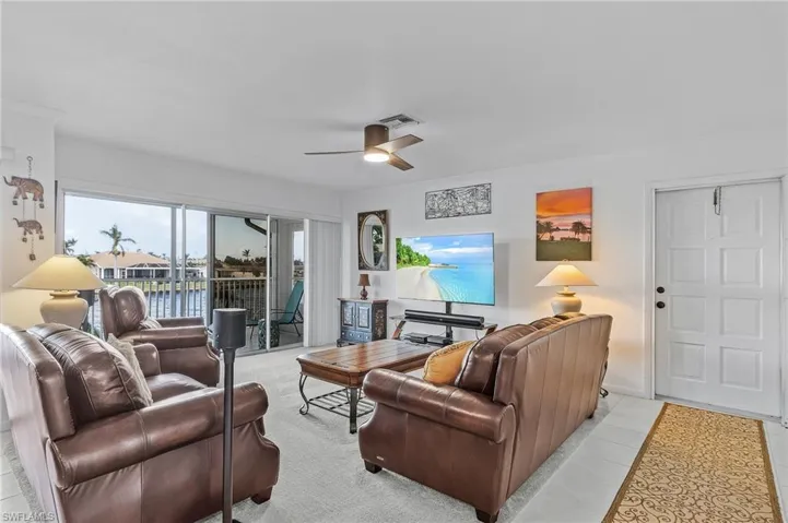 Tiled living room with ornamental molding and ceiling fan