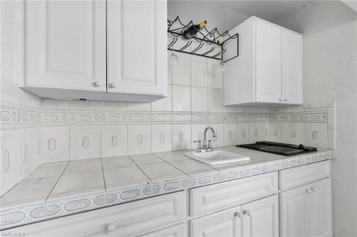 Kitchen with black gas cooktop, white cabinetry, sink, and tile counters