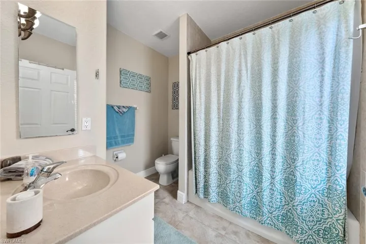 Bathroom with tile patterned floors, toilet, vanity, baseboards, and visible vents