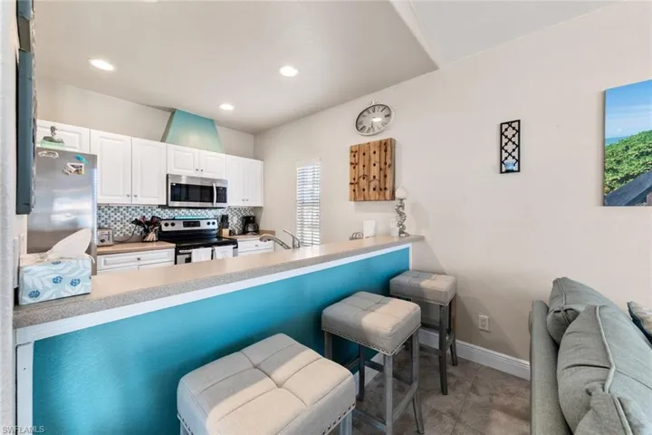 Kitchen with white cabinets, a peninsula, tasteful backsplash, and appliances with stainless steel finishes