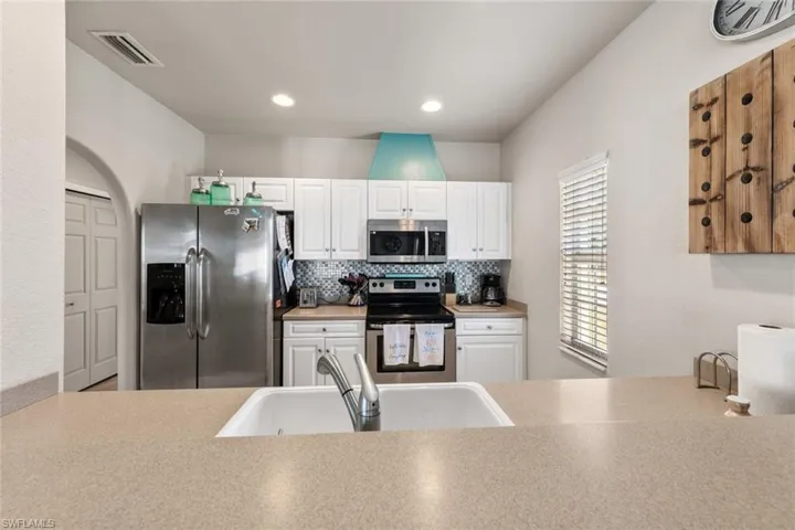 Kitchen featuring tasteful backsplash, stainless steel appliances, a sink, visible vents, and white cabinets