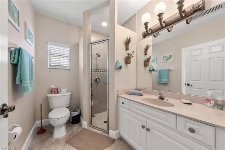 Full bath featuring tile patterned floors, toilet, vanity, a shower stall, and visible vents