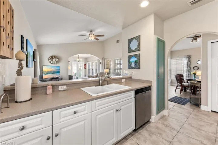 Kitchen with arched walkways, ceiling fan, a sink, and dishwasher