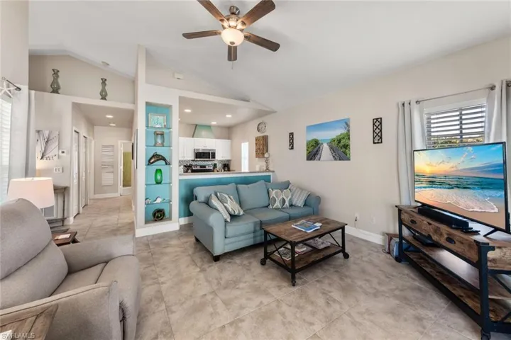 Living room featuring baseboards, lofted ceiling, ceiling fan, and light tile patterned floors