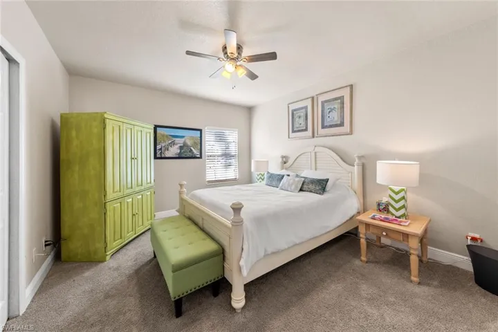 Bedroom featuring light colored carpet, ceiling fan, and baseboards