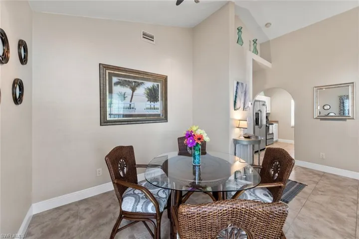Dining space with light tile patterned floors, arched walkways, baseboards, and visible vents