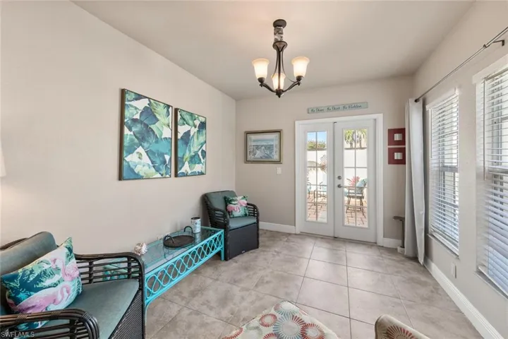 Living area with light tile patterned flooring, baseboards, french doors, and an inviting chandelier