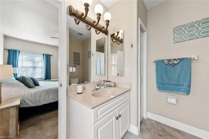 Ensuite bathroom featuring vanity, toilet, baseboards, tile patterned floors, and visible vents